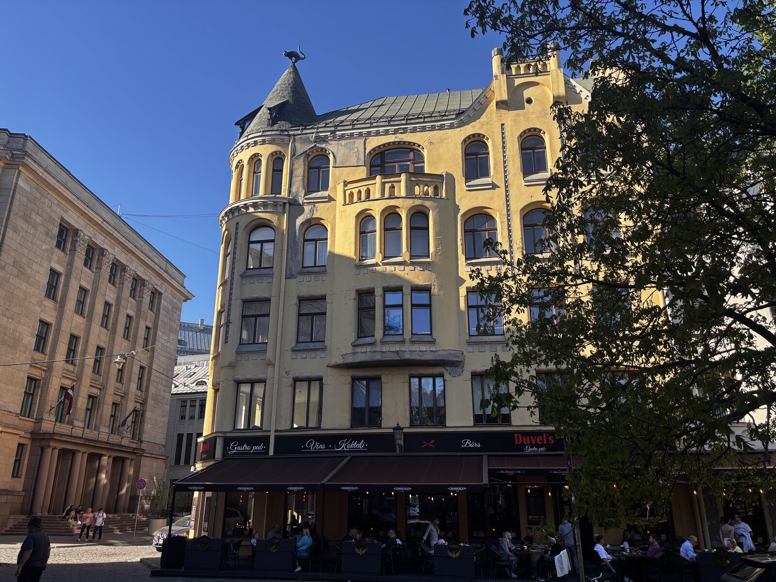 Das Katzenhaus (Kaķu nams) an der Meistaru iela in der Rigaer Altstadt, mit seiner gelben Jugendstilfassade und der Bronzekatze auf dem Eckt&uuml;rmchen, Lettland.