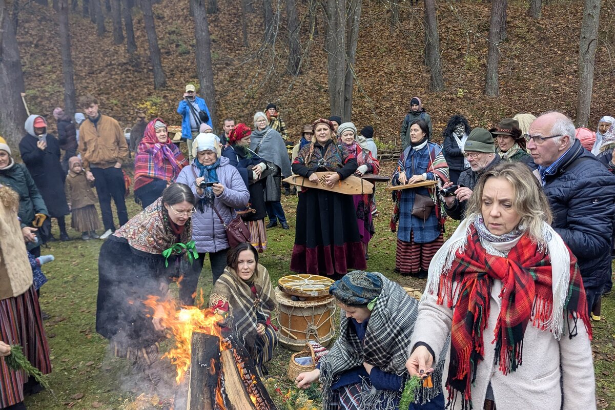 Besucher in Volkstracht am Mārtiņdiena-Lagerfeuer im lettischen Ethnographischen Freilichtmuseum, Riga.