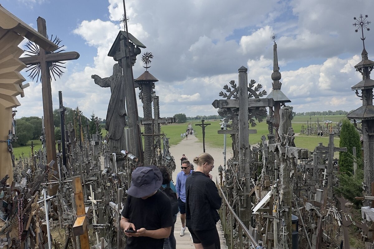 Berg der Kreuze, Litauen — Holzsteg mit Jesus-Statue und handgeschnitzten Kreuzen.