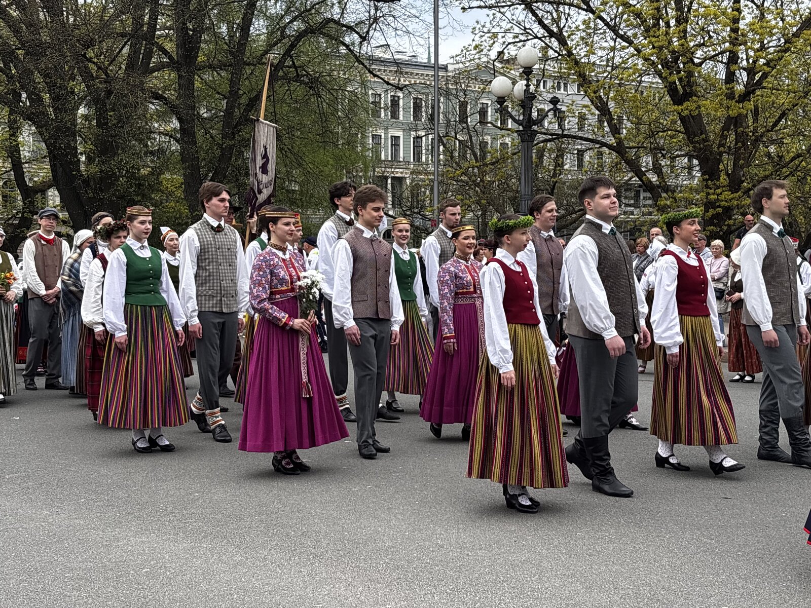 Trachtenumzug am Freiheitsdenkmal mit hochgehaltener lettischer Flagge, Riga, 4. Mai