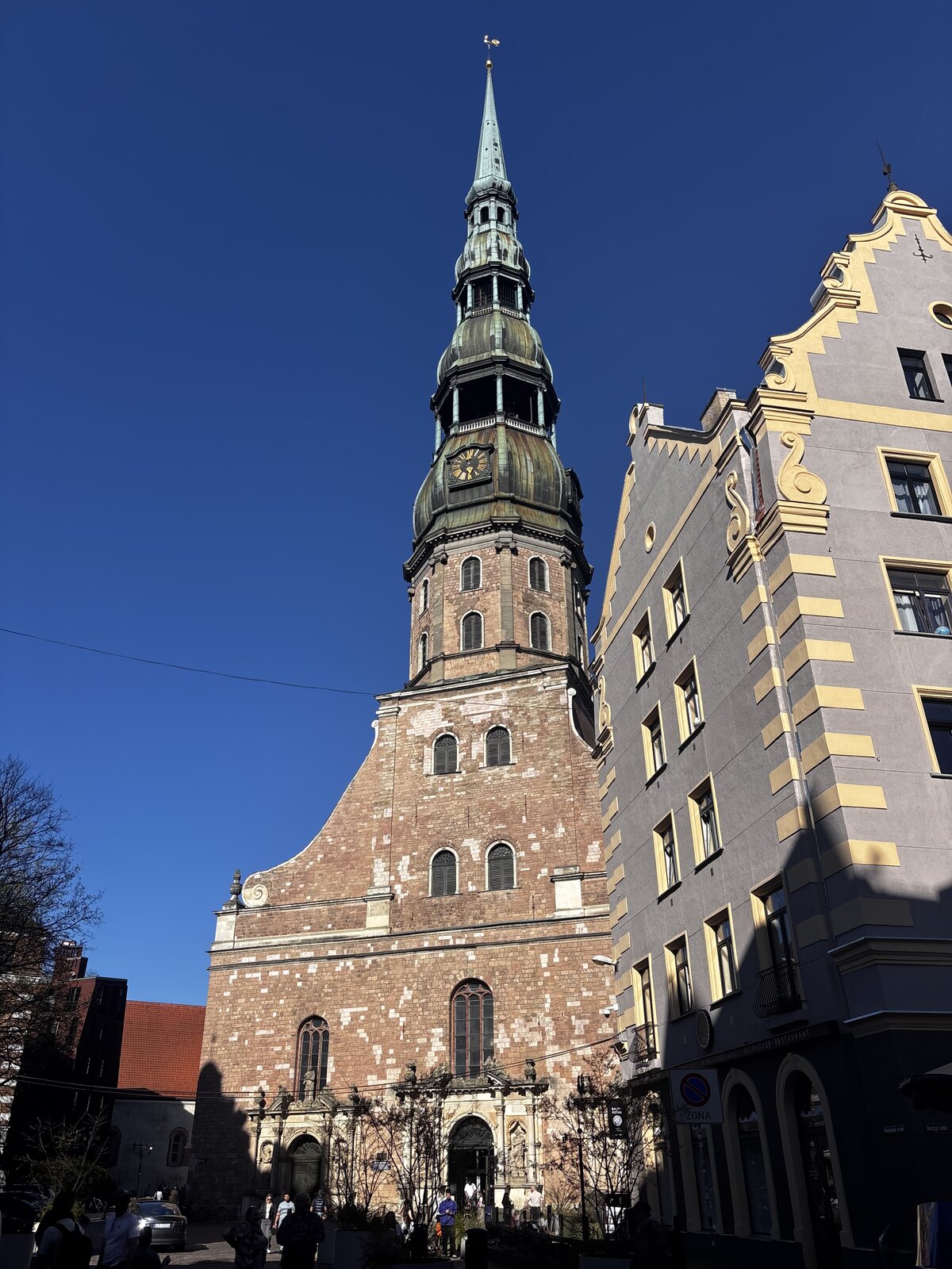 Die Petrikirche (Sv. Pētera baznīca) mit ihrem hohen gr&uuml;nen Turmhelm vor blauem Himmel in der Rigaer Altstadt, Lettland.