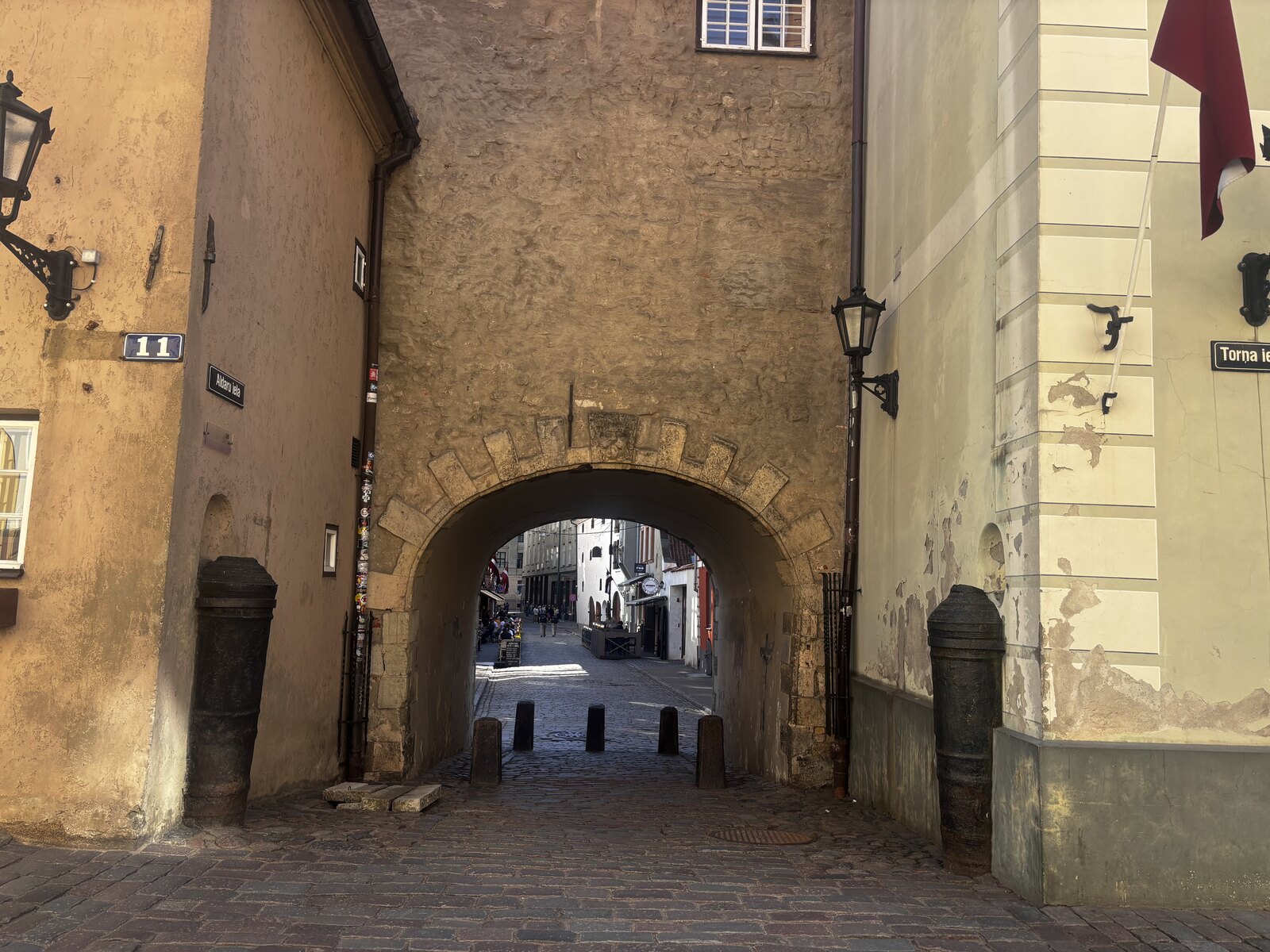 Das Schwedische Tor (Zviedru vārti) an der Torņa iela in der Rigaer Altstadt, Lettland &mdash; ein steinerner Torbogen zwischen zwei gelben Geb&auml;uden.