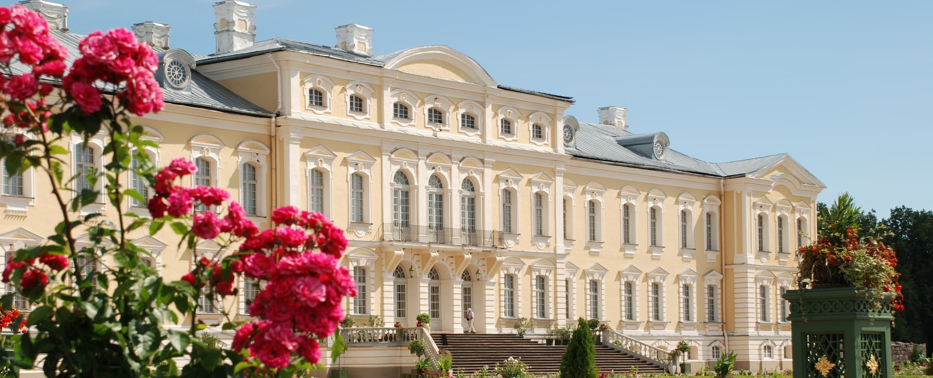 Barockfassade von Schloss Rundāle gerahmt von sommerlichen Rosen