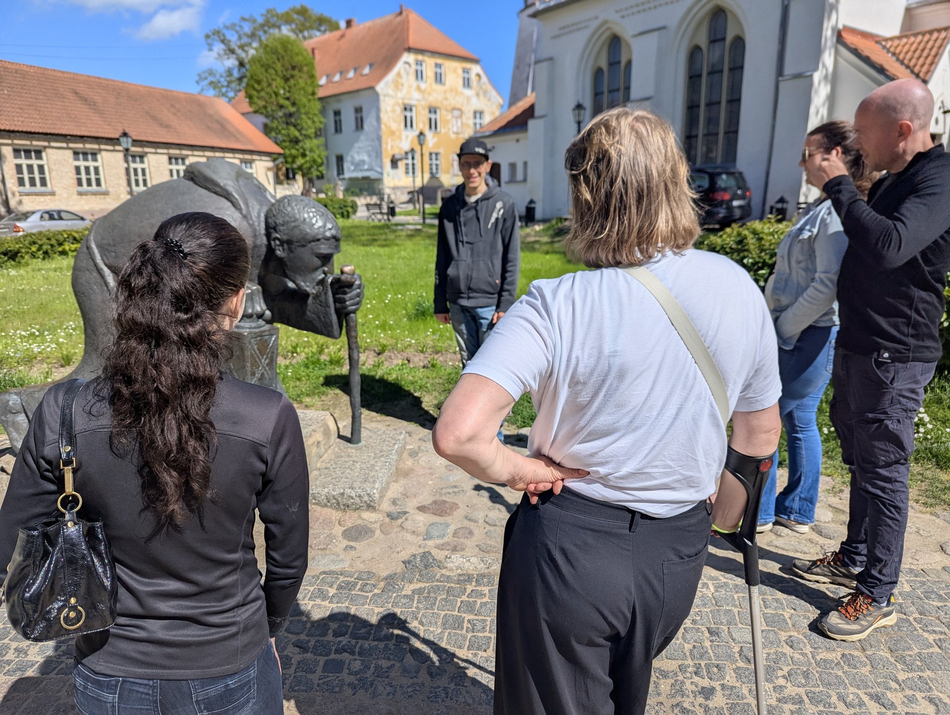 Reisegruppe um die Bronzeskulptur des Pilgers in der Altstadt von Cēsis