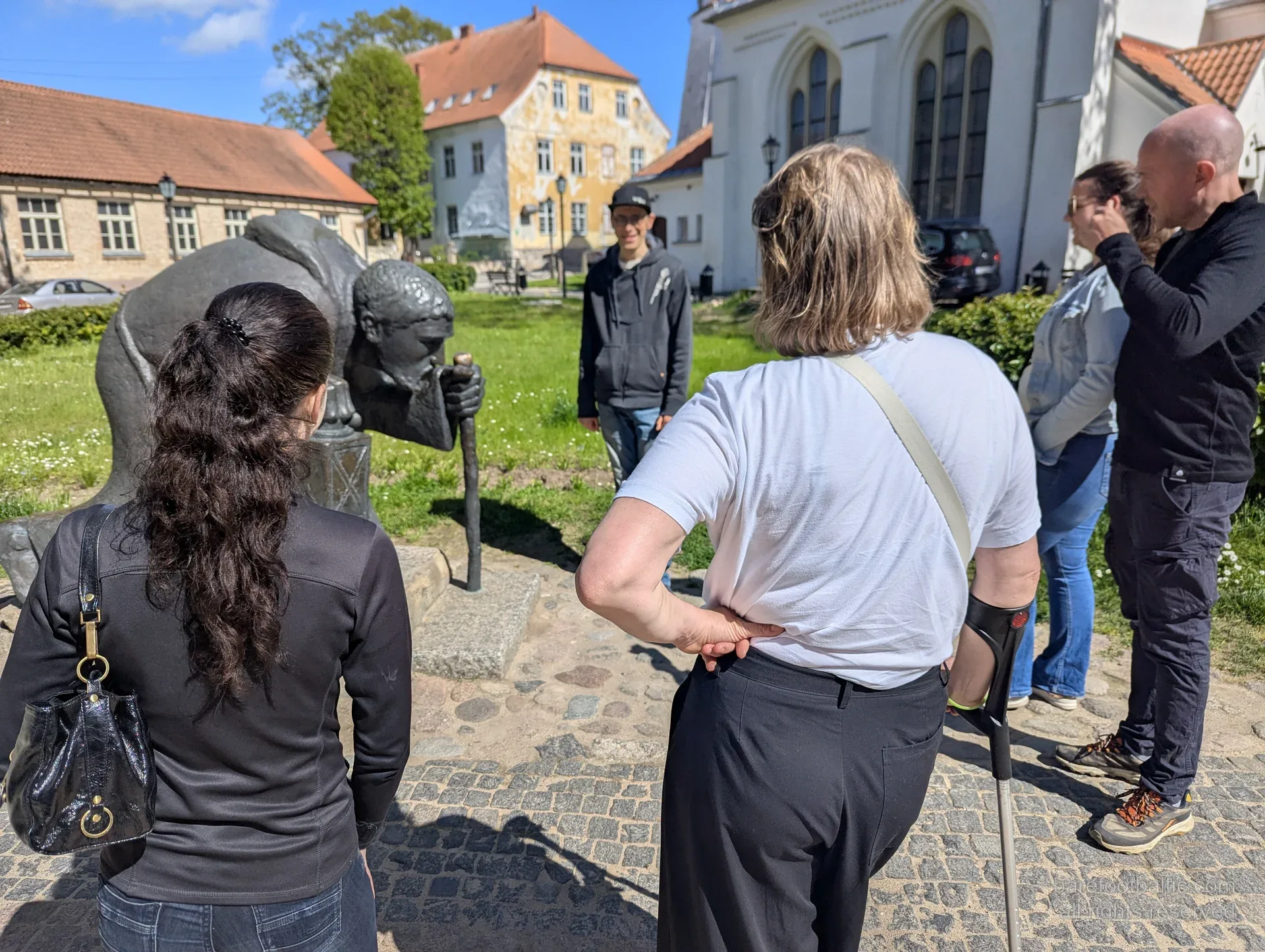 Reisegruppe um die Bronzeskulptur des Pilgers in der Altstadt von Cēsis