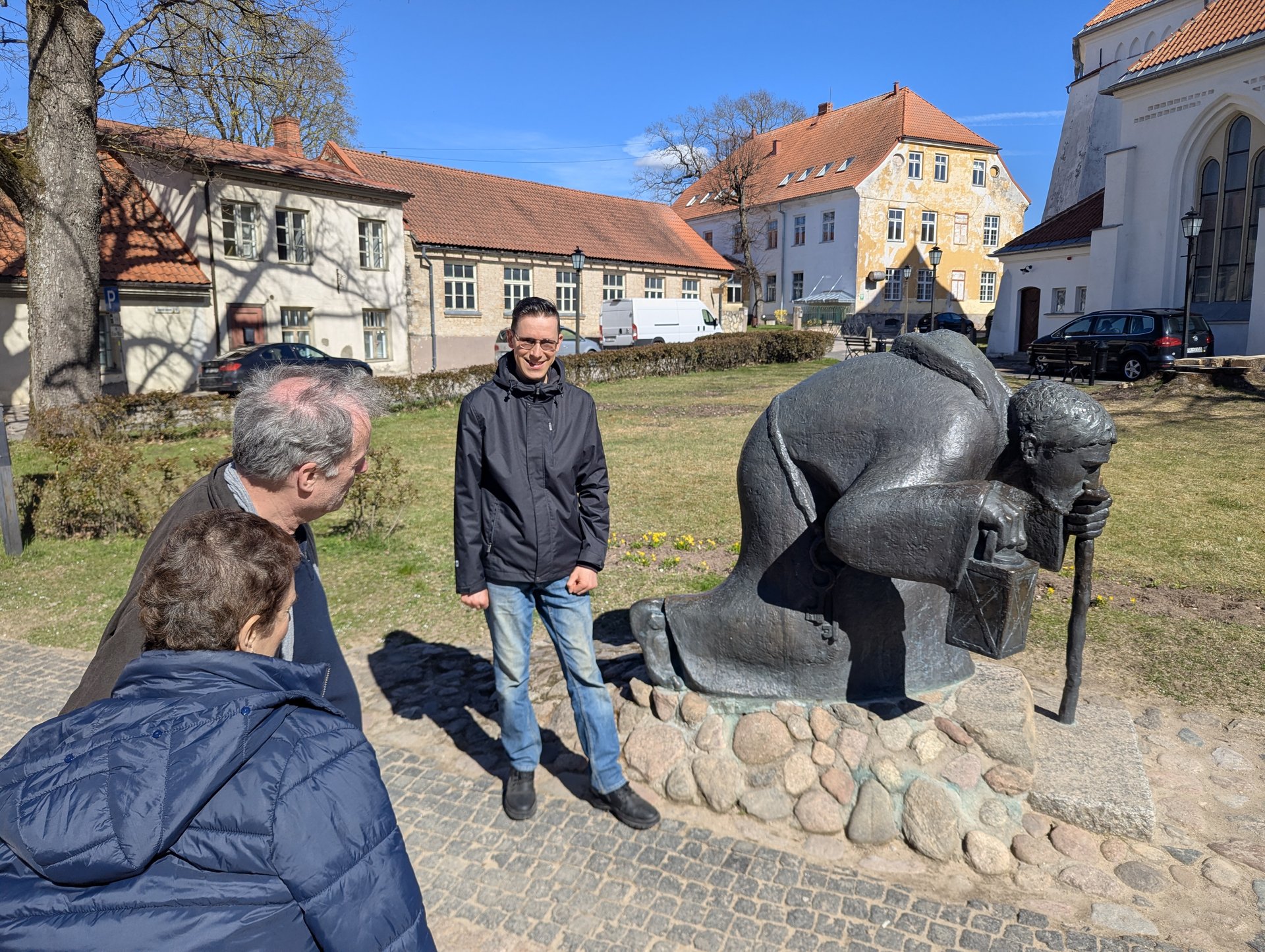 Reisegruppe neben der Bronzeskulptur des Pilgers in Cēsis