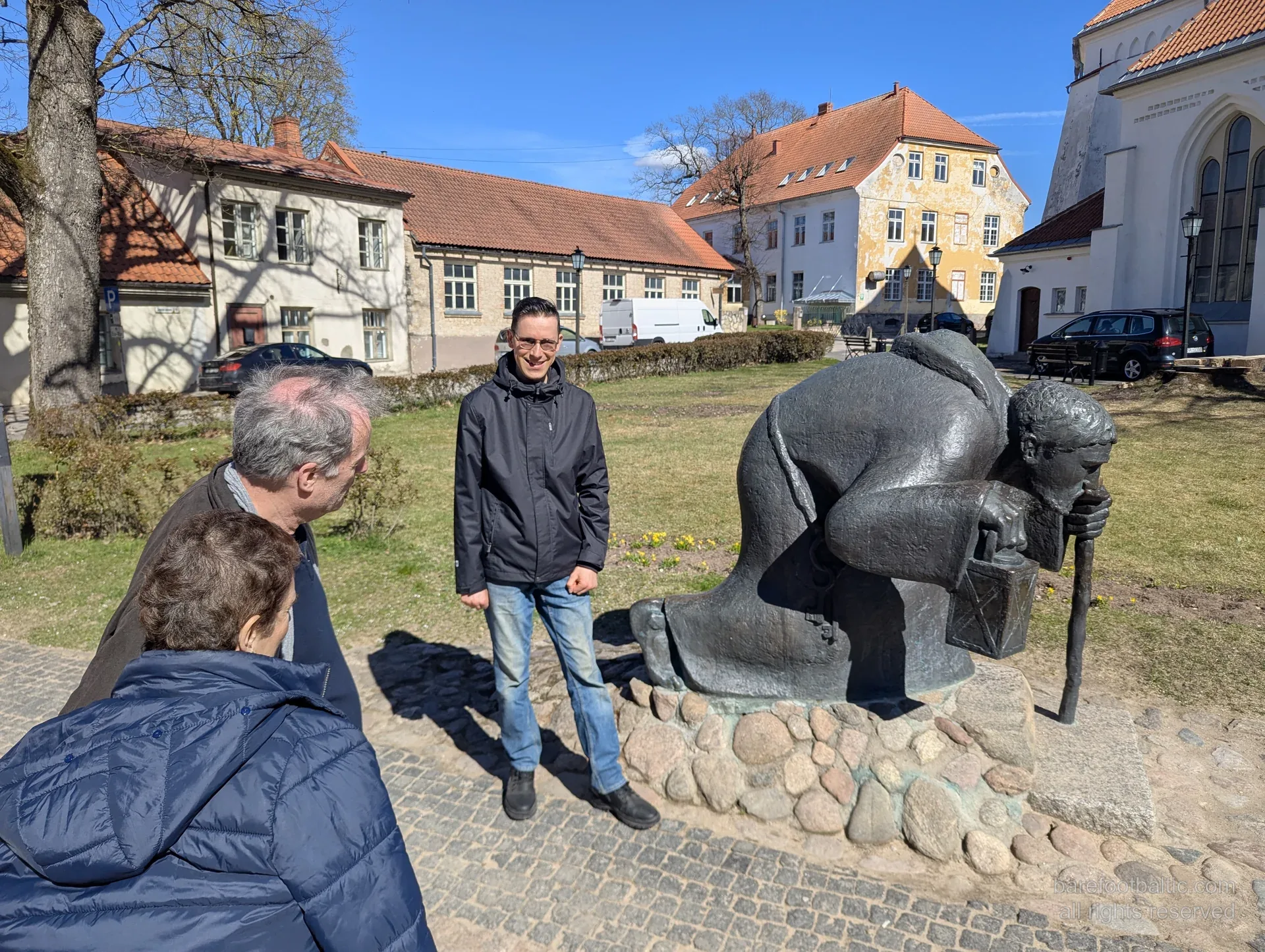 Reisegruppe neben der Bronzeskulptur des Pilgers in Cēsis
