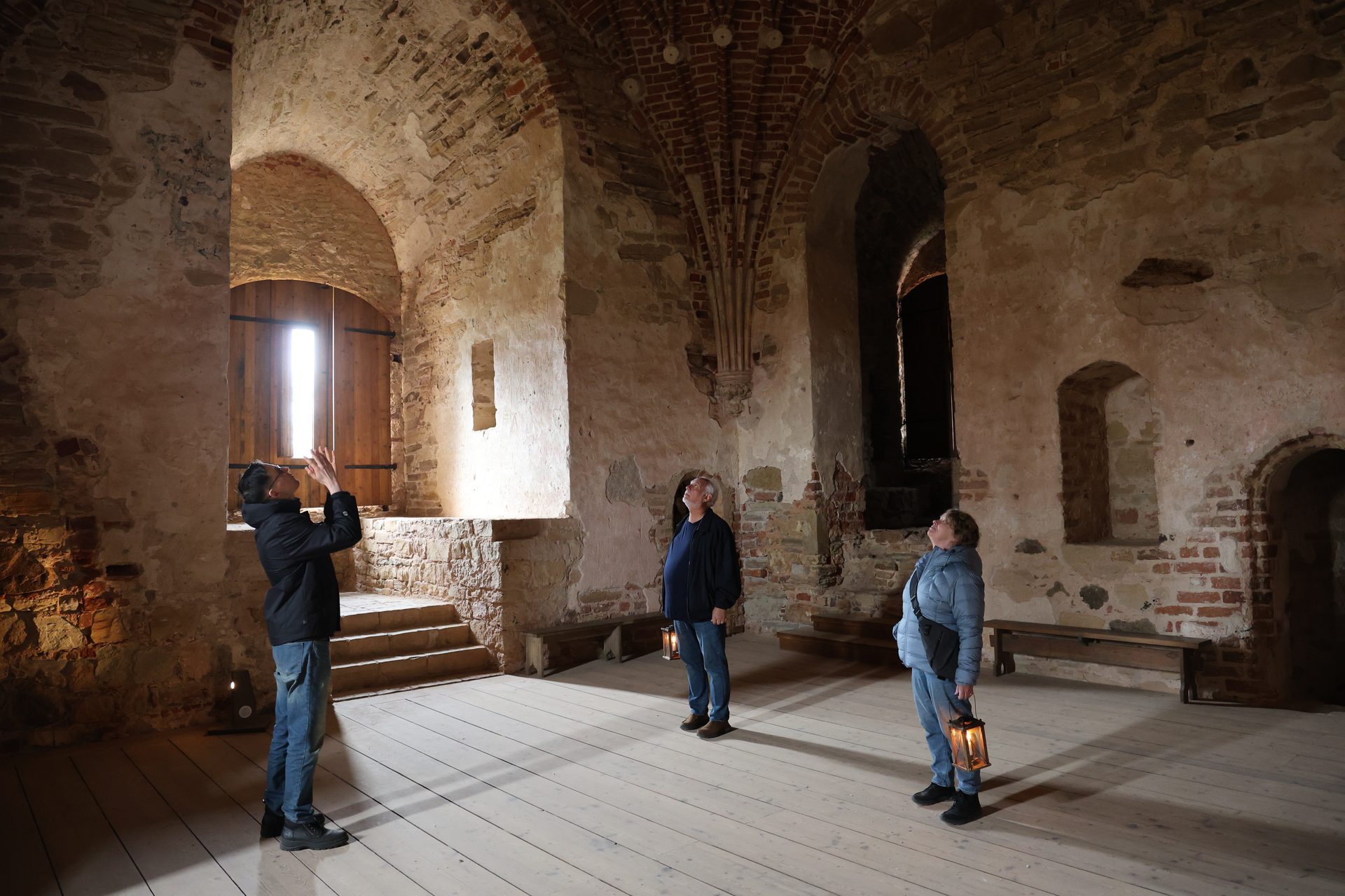 Gäste mit Kerzenlaternen im Inneren der Mittelalterlichen Burg Cēsis
