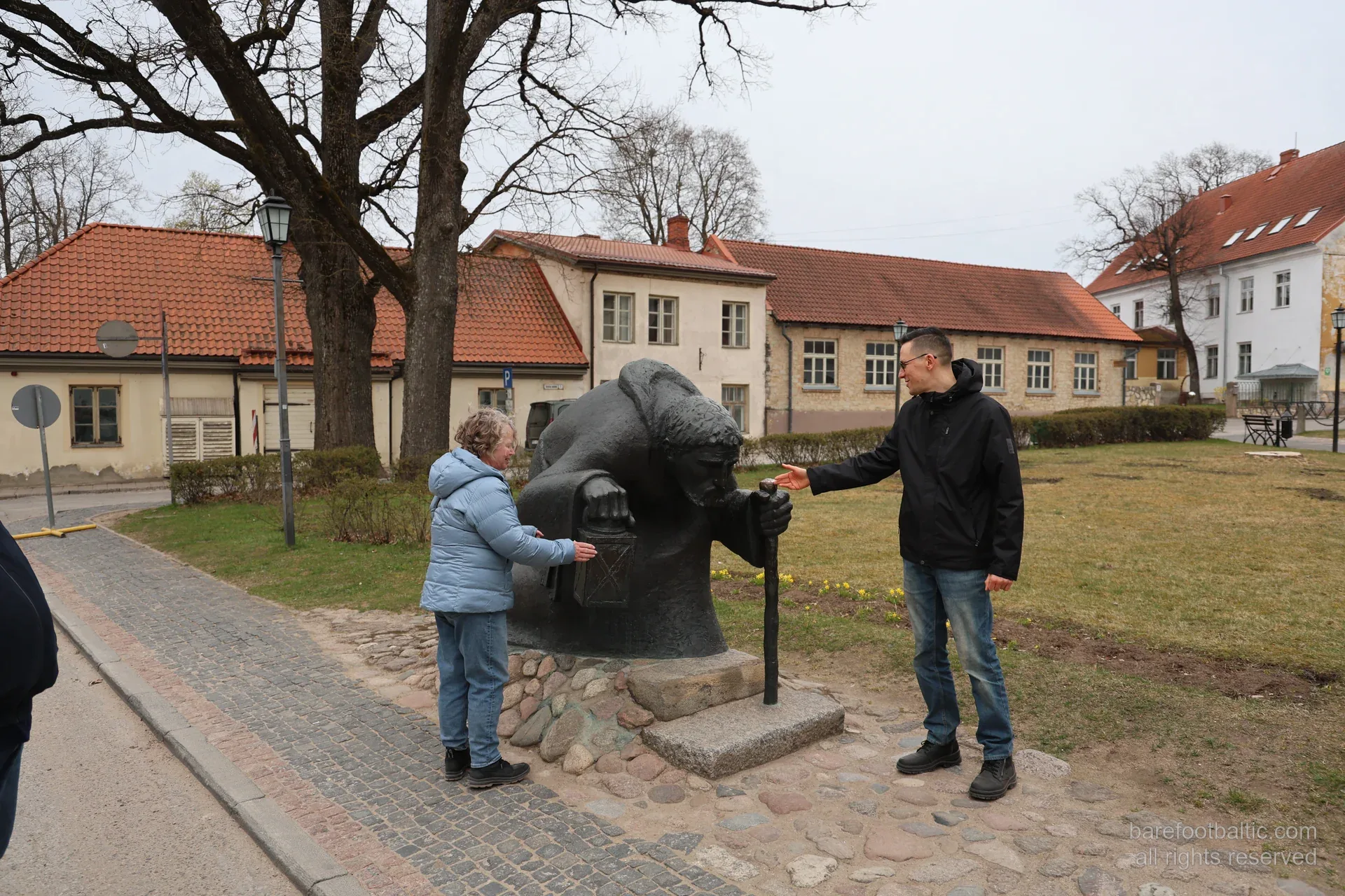 Reisegruppe an der Bronzeskulptur des Pilgers im Altstadtpark von Cēsis