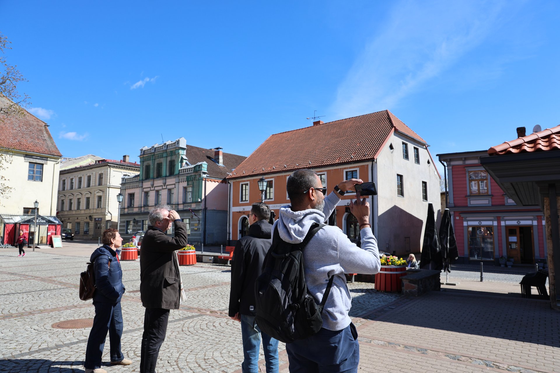 Reisegruppe fotografiert historische Fassaden auf dem Marktplatz der Altstadt von Cēsis