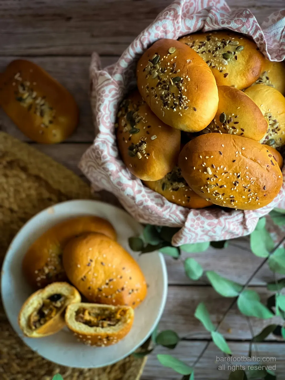 Ein Korb voll goldbrauner lettischer pīrāgi mit Kümmel bestreut, traditionelle kleine gefüllte Teigtaschen