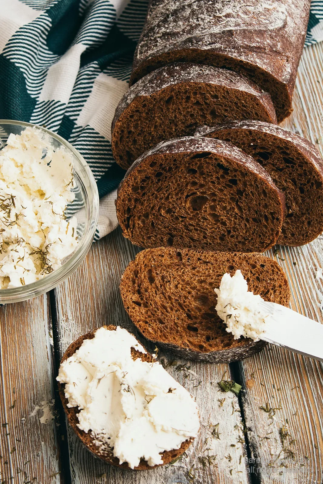 Scheiben von Rupjmaize-Roggenbrot neben einer Schale Biezpiens-Quark, bestreut mit Dill