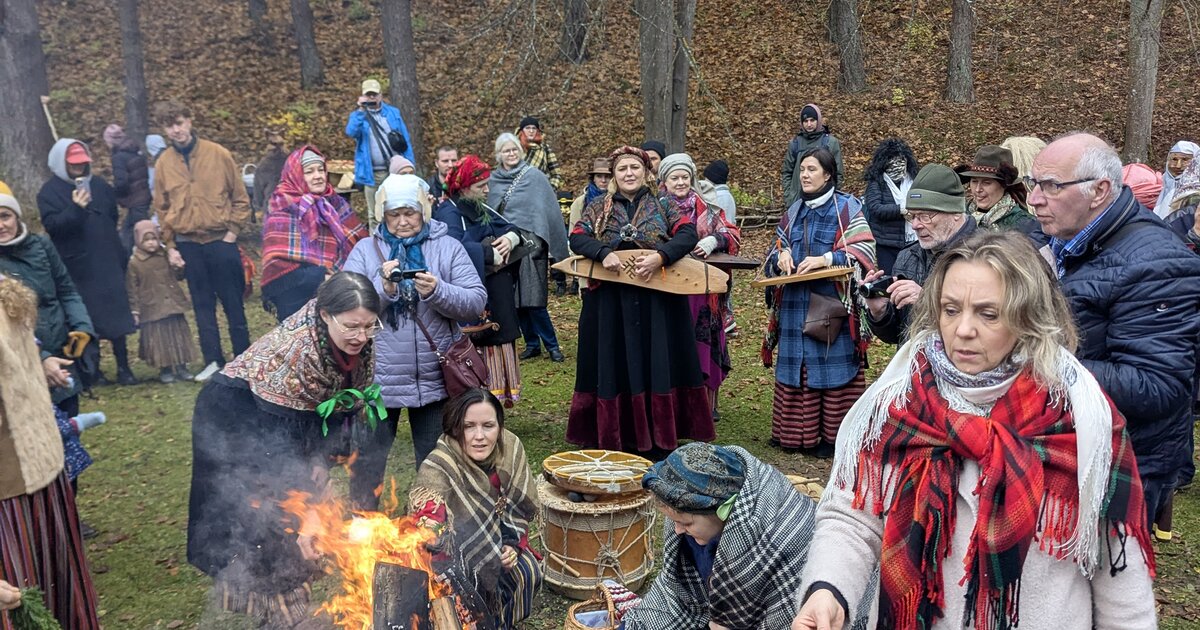 Besucher in Volkstracht am Mārtiņdiena-Lagerfeuer im lettischen Ethnographischen Freilichtmuseum, Riga.
